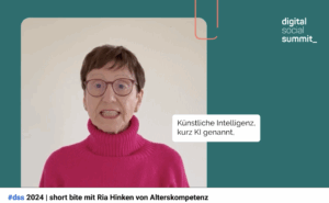 Screenshot. Ria Hinken in einem erdbeerfarbenen Pulli erklärt KI für Ältere